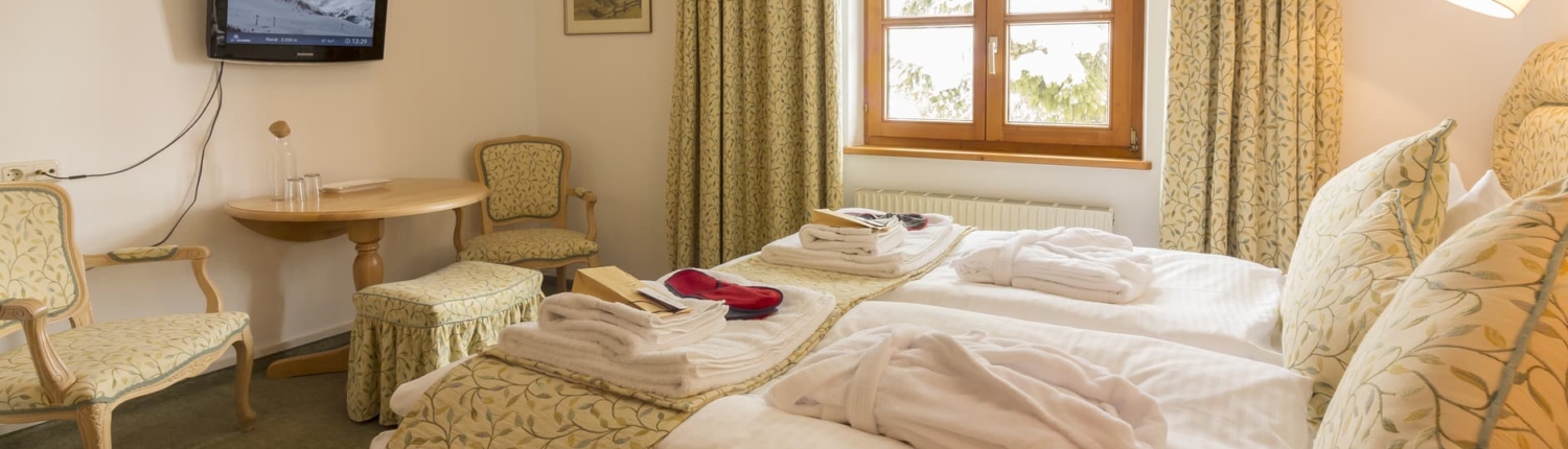 Ein helles, schön gemustertes Familien-Hotelzimmer mit frischen Bademäntel, Handtücher und Bettbezug