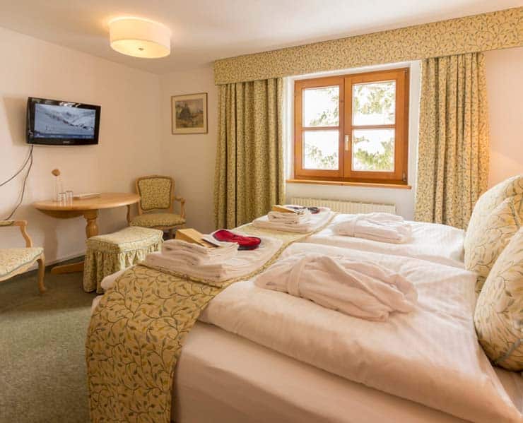 A bright patterned family hotel room with fresh robes, towels & linens on bed.