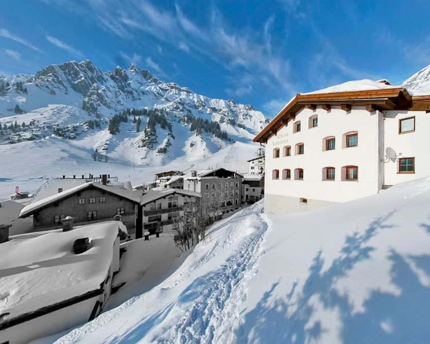A snowy outside view of Haus 7 Hotel with the Arlberg's picturesque Erzberg mountain in the background. 